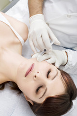 Obraz na płótnie Canvas Top view young woman receives cosmetic injection from doctor