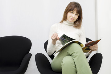 young caucasian woman sitting in the waiting room for doctors
