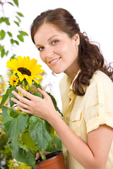 Smiling woman holding flower pot with sunflower