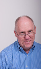 Older Balding Man in Blue Shirt and Glasses Smiling