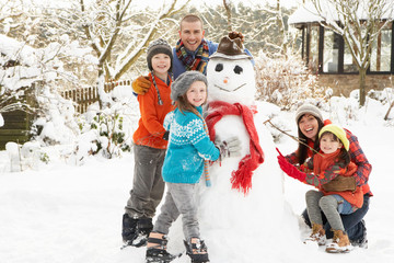 Family Building Snowman In Garden