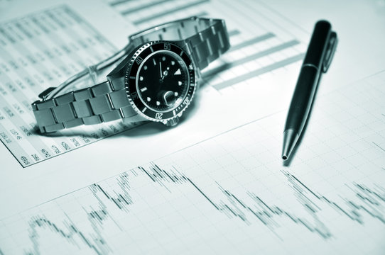 Men's watch and pen on a market report