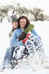 Fototapeta na wymiar Couple Sledging Through Snowy Woodland