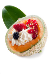 mix of berries fruits over whipped cream on open melon