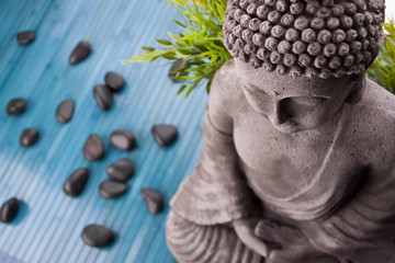 Buddha mit Bambus, Massage Steinen und Schale mit Blüten