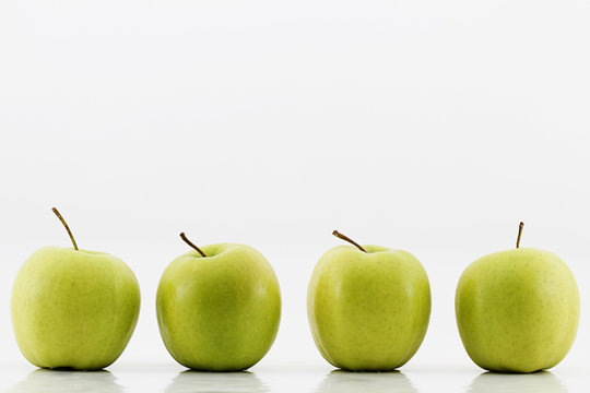 vier gruene Äpfel auf weißem Hintergrund