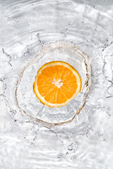 Fototapeta na wymiar Fresh orange dropped into water with bubbles isolated on white