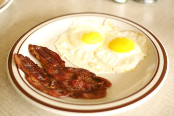breakfast consisting of eggs sunnyside up and bacon