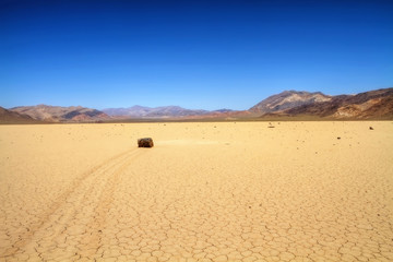 Fototapeta na wymiar Moving rock on cracked desert ground