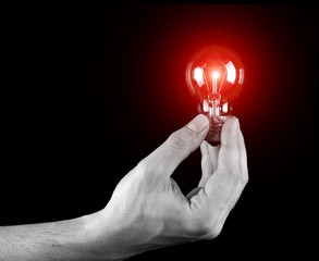 Hand holding light bulb isolated on black
