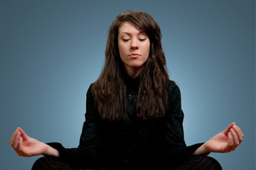 Attractive girl in dark clothes meditating