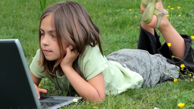 fillette faisant de l'ordinateur dans l'herbe