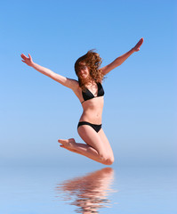 Obraz premium young beautiful woman jumps against the sea