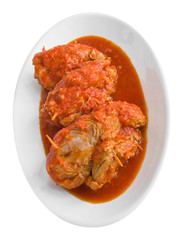 Meat roulade in tomato sauce on white dish.