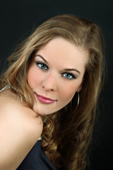 Fototapeta premium Beautiful girl with tilted head looks at camera on black