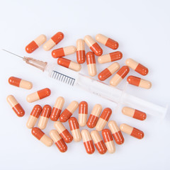 Syringe surrounded by two-coloured pills