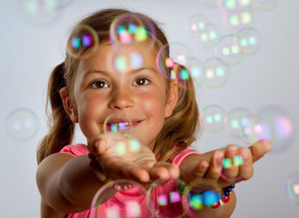 Pretty young girl catching bubbles that are floating in the air