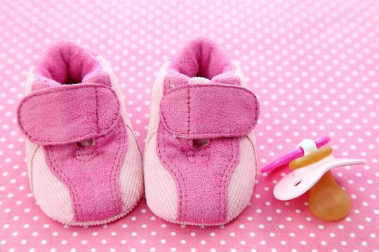 Pink baby shoes and dummy on spotted background - Powered by Adobe