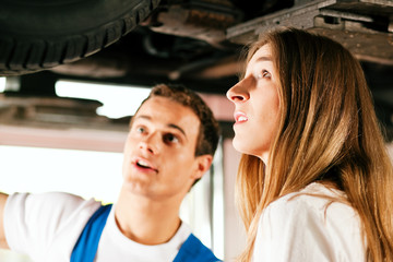 Frau spricht mit Automechaniker in Werkstatt