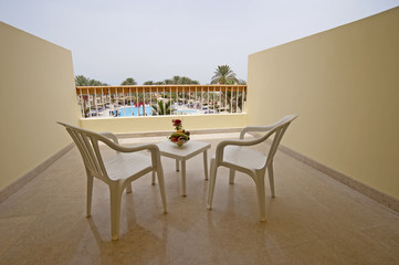 Table and chairs on a hotel balcony with a pool view