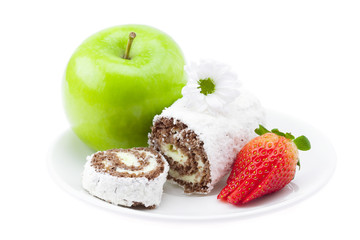cake roll, apple and strawberry on a plate isolated on white