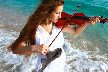 young attractive woman playing violin on sea background