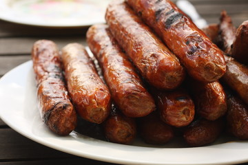 Plate of barbequed sausages on wooden table