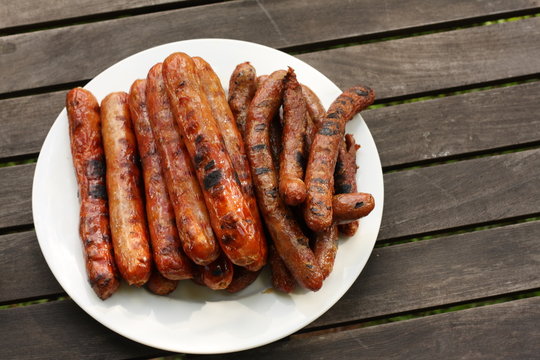 Plate of barbequed sausages on wooden table