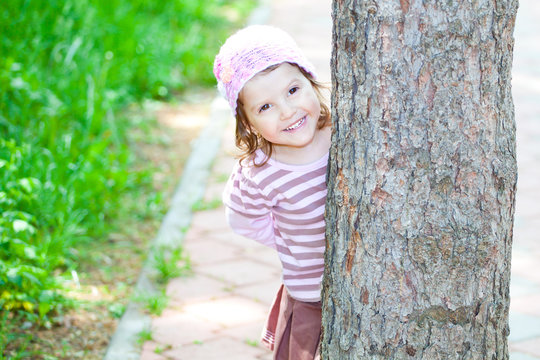 Little girl hiding behind a tree