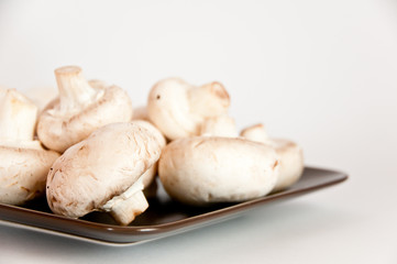 White mushrooms on a brown plate