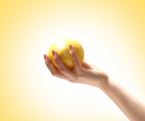 A yellow tasty lemon held in a young female hand