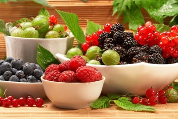 Berries in plates, on a table, among green leaves