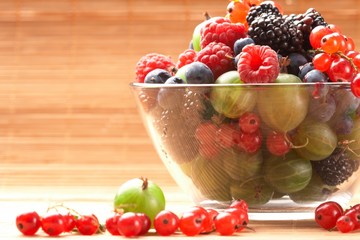 Fruit mix in the glass container, on a table from straw