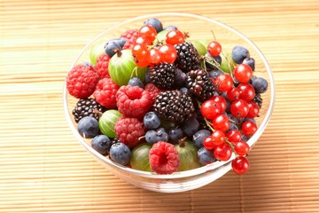 Fruit mix in the glass container, on a table from straw