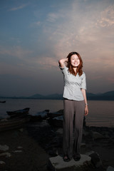 Beautiful young woman on the beach at sunset .