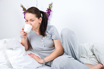 Woman drinking coffee and lying on bed