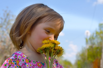 Portrait of cute little girl with yellow dandelions