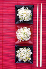 Reis mit Essstäbchen auf roter Matte