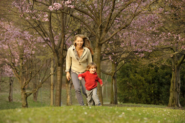 Naklejka premium Blossom trees in the park with mother and child