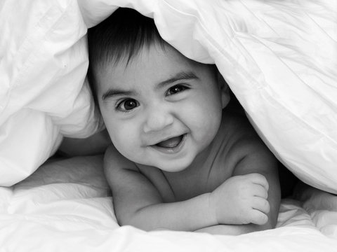 neonato sotto le coperte che ride