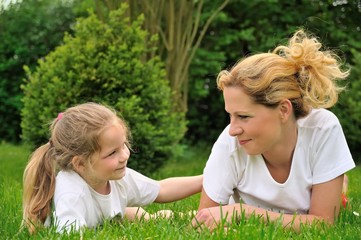 Young mother and daughter laying on the grass