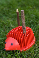 red plastic hedgehog with two wooden pencils on its back