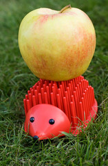 red plastic hedgehog with big natural apple on its back