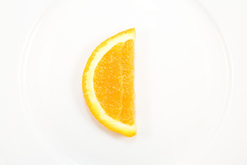 Orange slice, C shape symbolizing vitamin C, on white plate