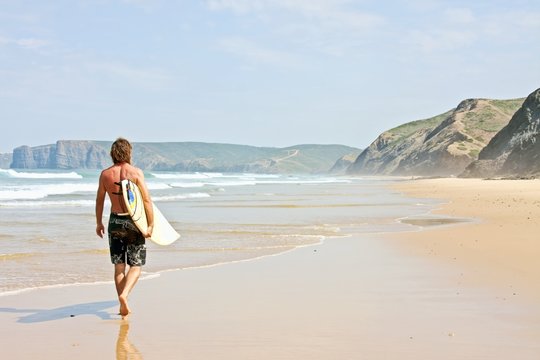 Surfer with his surfboard walking  at the beach