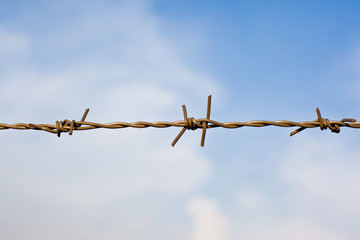 Barbed wire fence against a blue sky