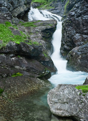 Small waterfall in black rocks. Northern Norway