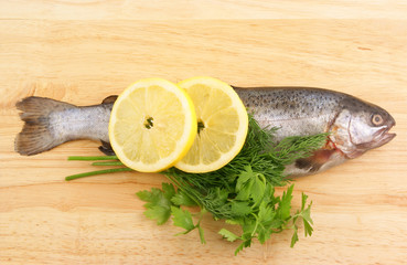 Raw fish with lemon and parsley on wooden background