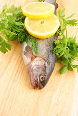 Raw fish with lemon and parsley on wooden background