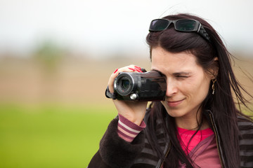 Young lady using video camera outdoors
